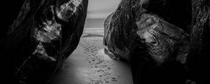 Preview wallpaper rocks, sand, footprints, sea, black and white