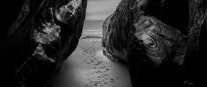 Preview wallpaper rocks, sand, footprints, sea, black and white