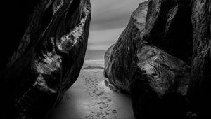 Preview wallpaper rocks, sand, footprints, sea, black and white