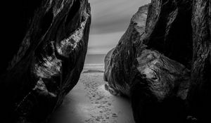 Preview wallpaper rocks, sand, footprints, sea, black and white