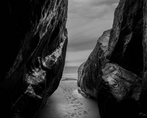 Preview wallpaper rocks, sand, footprints, sea, black and white