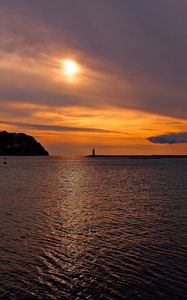 Preview wallpaper sea, bay, lighthouse, mountains, sunset, clouds, sun