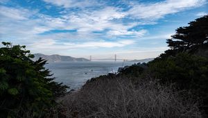 Preview wallpaper sea, bridge, mountains, trees, branches, view