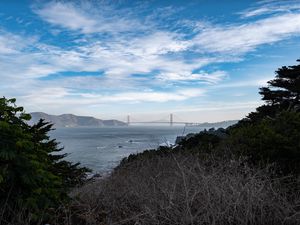 Preview wallpaper sea, bridge, mountains, trees, branches, view