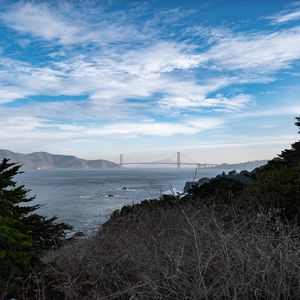 Preview wallpaper sea, bridge, mountains, trees, branches, view