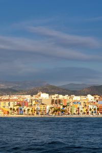 Preview wallpaper sea, buildings, mountains, city, clouds