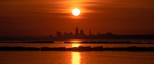 Preview wallpaper sea, city, skyscrapers, sunset, rays, dark