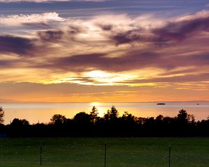 Preview wallpaper sea, clouds, trees, field, evening