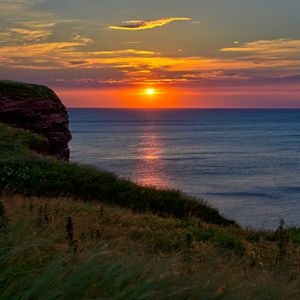 Preview wallpaper sea, coast, grass, sunset