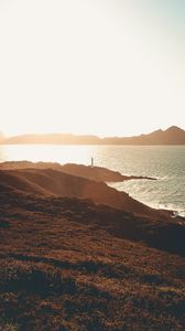 Preview wallpaper sea, coast, hills, lighthouse, sunlight