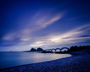 Preview wallpaper sea, coast, stones, bridge, sunset, evening