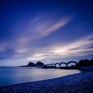 Preview wallpaper sea, coast, stones, bridge, sunset, evening