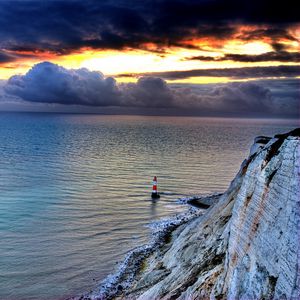 Preview wallpaper sea, lighthouse, rock, sunset