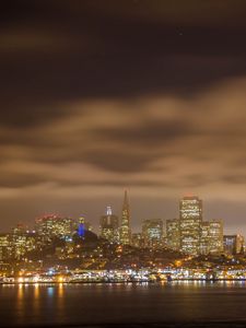 Preview wallpaper sea, lights, skyscrapers, clouds, sky, city