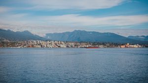 Preview wallpaper sea, mountains, buildings, city, clouds