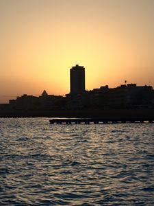 Preview wallpaper sea, pier, buildings, city, silhouettes, evening