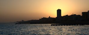 Preview wallpaper sea, pier, buildings, city, silhouettes, evening