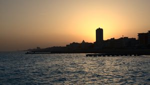 Preview wallpaper sea, pier, buildings, city, silhouettes, evening