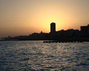 Preview wallpaper sea, pier, buildings, city, silhouettes, evening