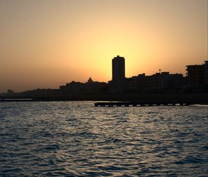 Preview wallpaper sea, pier, buildings, city, silhouettes, evening