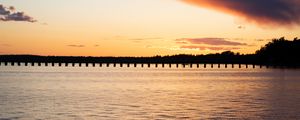 Preview wallpaper sea, pier, pilings, trees, evening, silhouettes