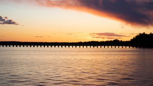 Preview wallpaper sea, pier, pilings, trees, evening, silhouettes