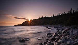 Preview wallpaper sea, sunset, stones, shore, trees