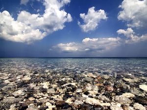 Preview wallpaper sea, water, transparent, stones, bottom, clouds, sky