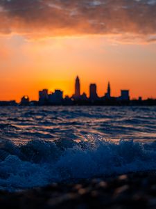 Preview wallpaper sea, waves, city, buildings, silhouettes, sunset