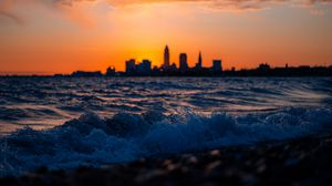 Preview wallpaper sea, waves, city, buildings, silhouettes, sunset