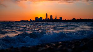 Preview wallpaper sea, waves, city, buildings, silhouettes, sunset