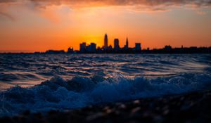 Preview wallpaper sea, waves, city, buildings, silhouettes, sunset