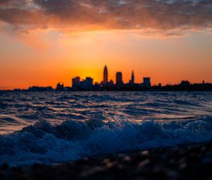 Preview wallpaper sea, waves, city, buildings, silhouettes, sunset