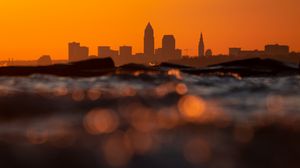 Preview wallpaper sea, waves, city, silhouettes, sunset