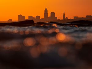 Preview wallpaper sea, waves, city, silhouettes, sunset