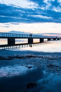 Preview wallpaper shore, bridge, silhouettes, sea, water, twilight