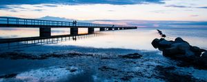 Preview wallpaper shore, bridge, silhouettes, sea, water, twilight