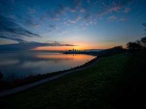 Preview wallpaper shore, water, horizon, buildings, sunset, dark