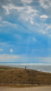 Preview wallpaper silhouette, alone, coast, sea, clouds, rays, light