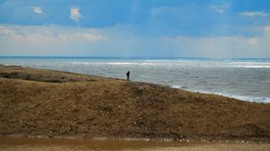 Preview wallpaper silhouette, alone, coast, sea, clouds, rays, light