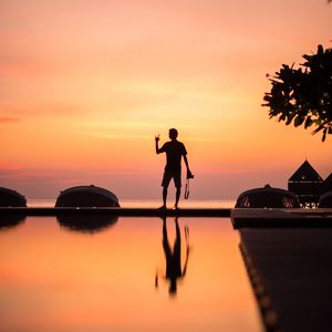 Preview wallpaper silhouette, alone, photographer, water, reflection, sunset, dark