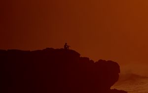 Preview wallpaper silhouette, alone, rock, sea, dusk