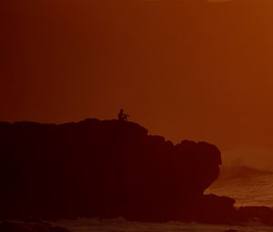 Preview wallpaper silhouette, alone, rock, sea, dusk