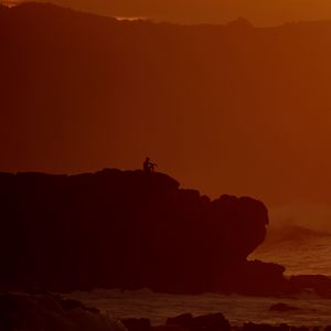 Preview wallpaper silhouette, alone, rock, sea, dusk