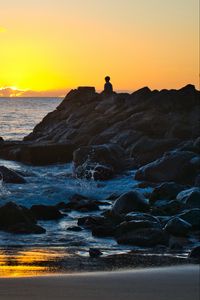 Preview wallpaper silhouette, alone, rocks, sea, horizon, sunset