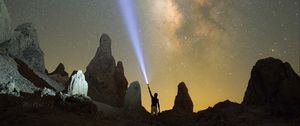 Preview wallpaper silhouette, man, lantern, glow, starry sky, rocks