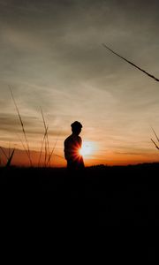 Preview wallpaper silhouette, man, light, sunset, sky, grass