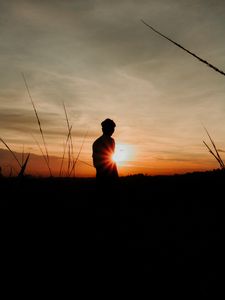 Preview wallpaper silhouette, man, light, sunset, sky, grass