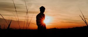 Preview wallpaper silhouette, man, light, sunset, sky, grass