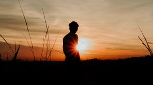 Preview wallpaper silhouette, man, light, sunset, sky, grass